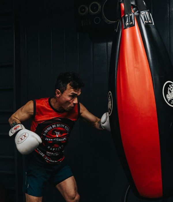 Athletic man performing a dynamic strength exercise in a minimalist dark gym.